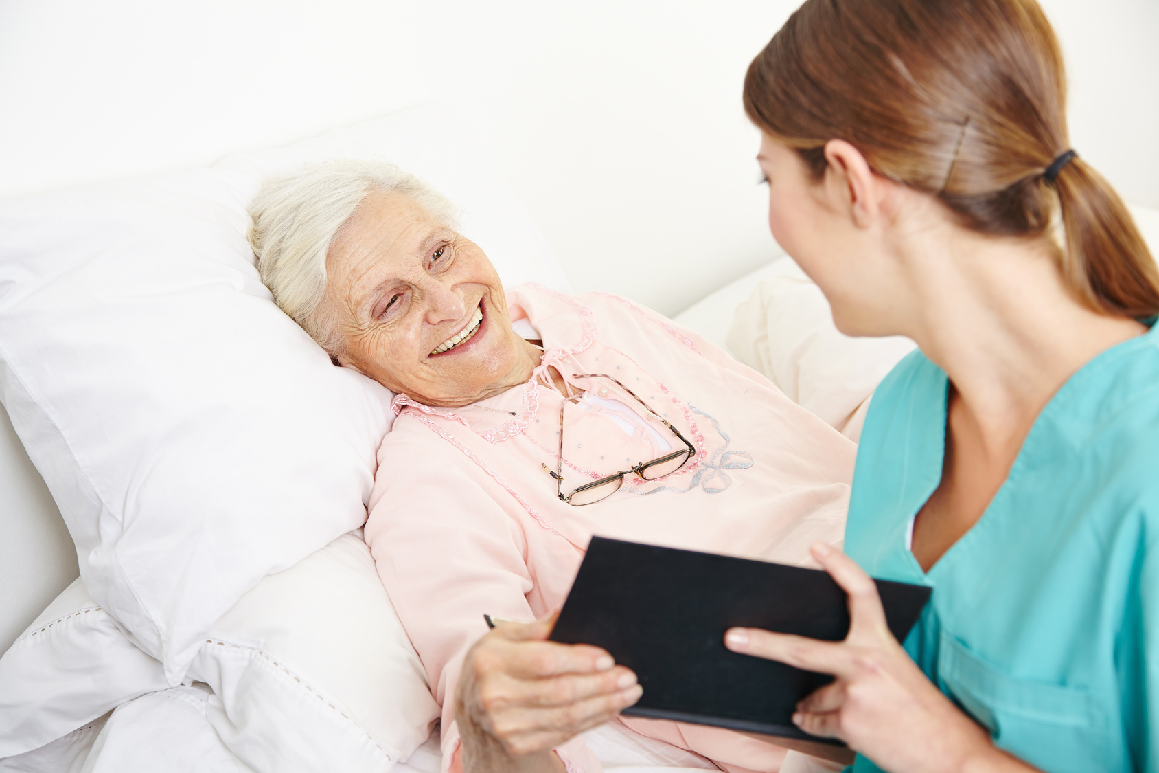Pflegerin kümmert sich um bettlägerige Seniorin im Fallmanagement.