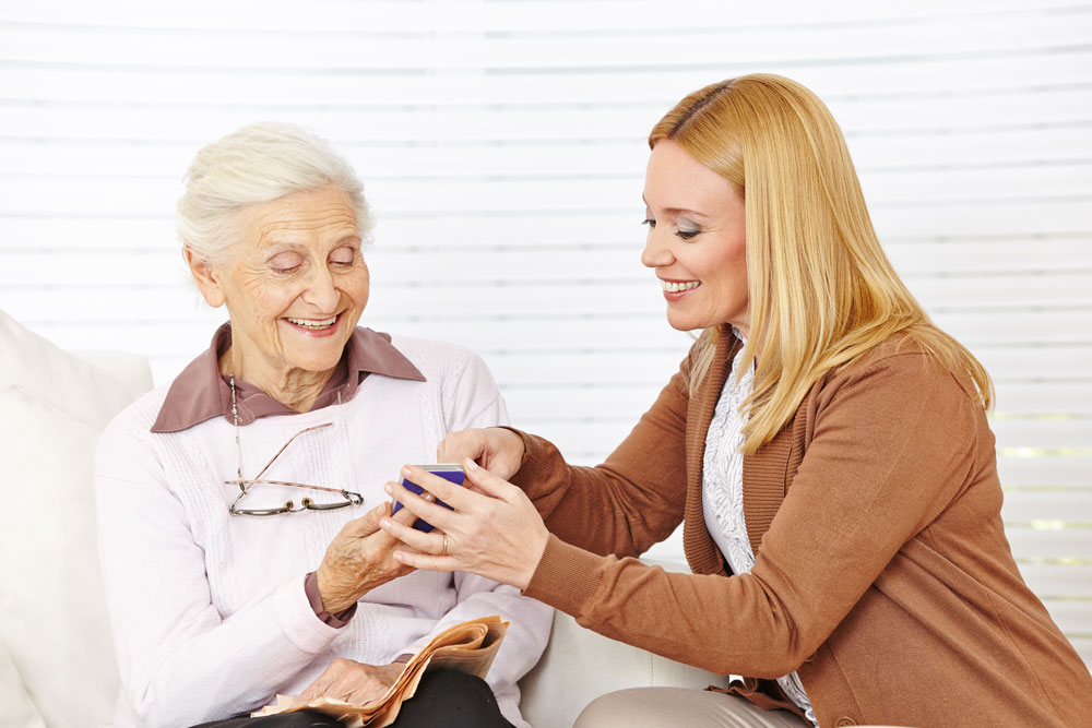 Klinische Sozialarbeit –Betreuerin erklärt Seniorin den Umgang mit dem Smartphone